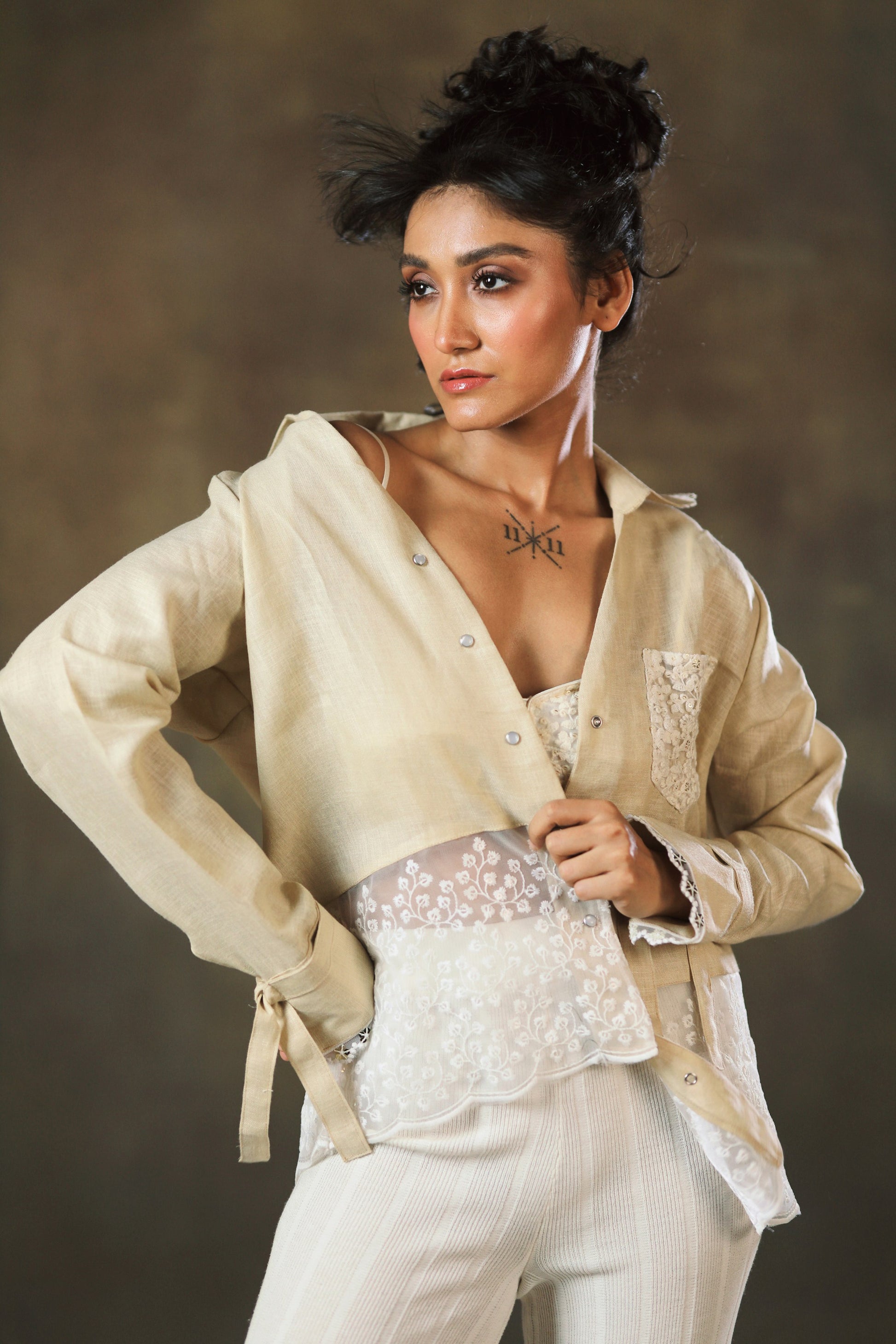 Tan Twist oversized shirt by 66aura, featuring a relaxed fit with twist detailing and long sleeves, displayed on a hanger.