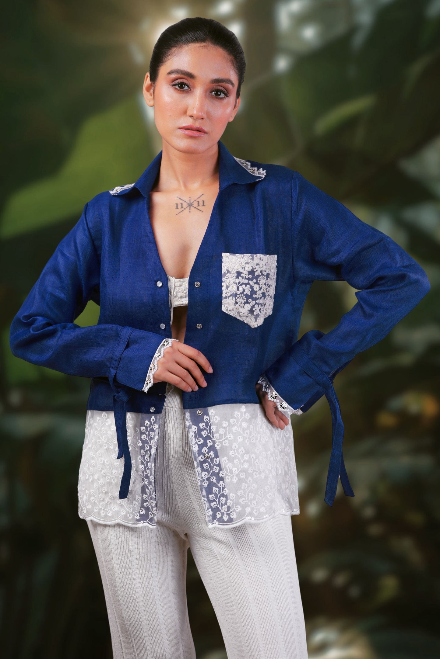 Model wearing a cobalt crush oversized shirt by 66aura, styled with a relaxed fit, standing on a carpeted floor with decorative props.