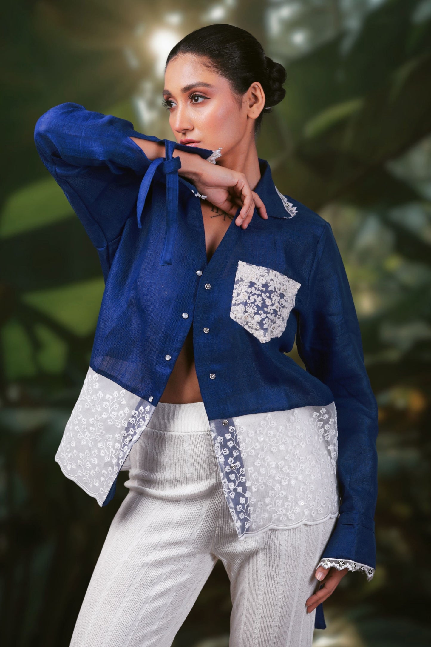 Model wearing a cobalt crush oversized shirt by 66aura, standing on a carpet with stylish props in the background.