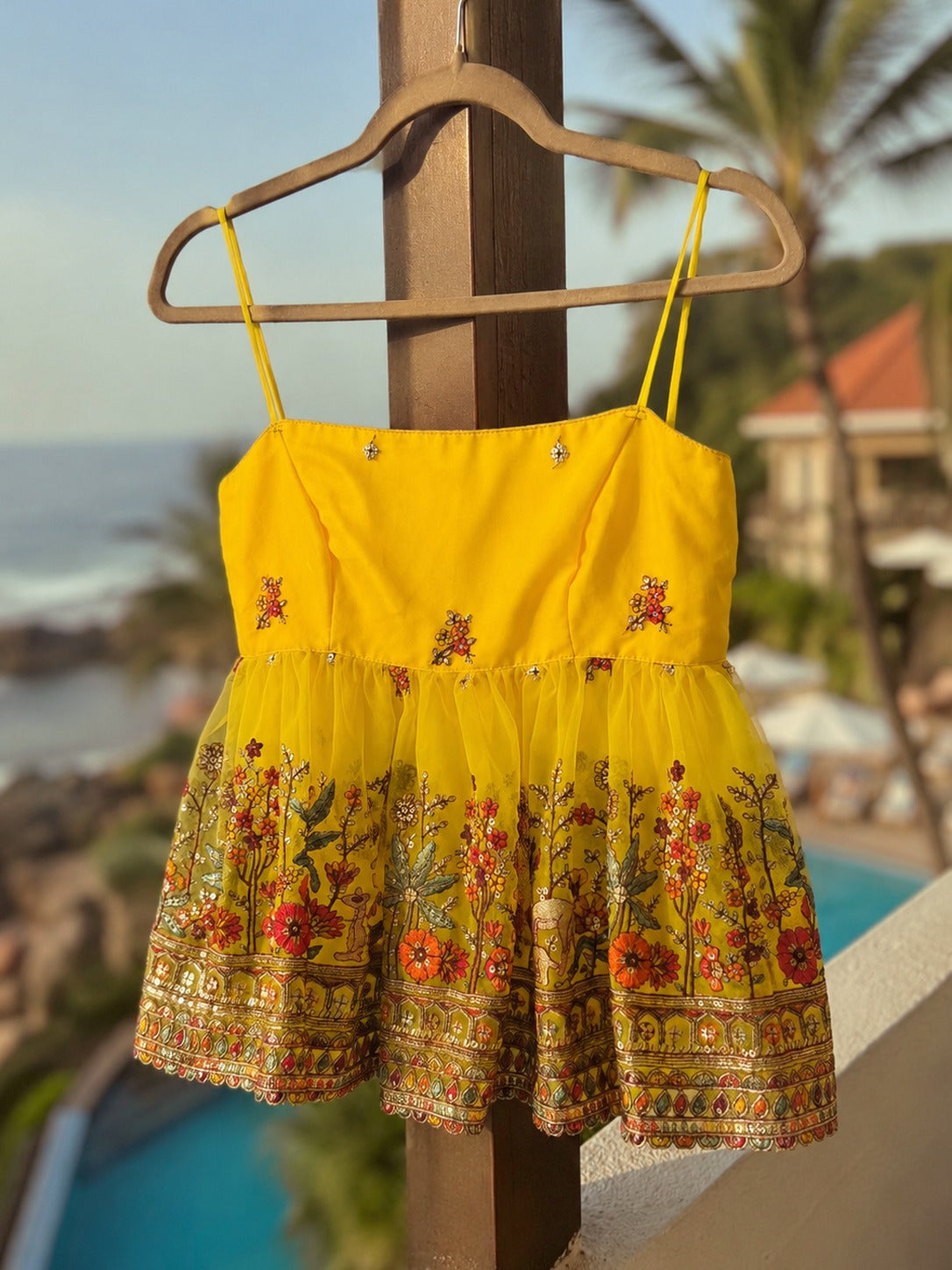 Yellow Malibu Morning Top by 66aura displayed hanging on a wooden hanger, showcasing its vibrant color and casual style.